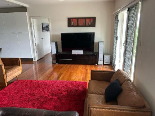 a living room with a couch and a flat screen tv at Hill top 2-bedroom home with charming view in Brisbane