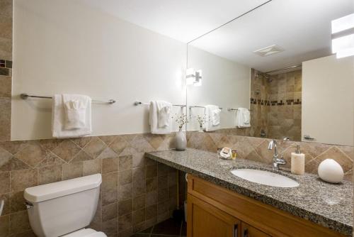 a bathroom with a toilet and a sink and a mirror at Glacier Lodge 216 by Outpost Whistler in Whistler