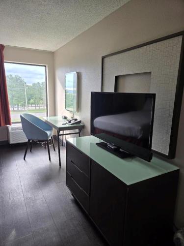 a living room with a television and a table with a chair at Hamilton Inn Birmingham-Bessemer in Bessemer