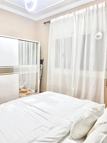 a bedroom with a white bed and a mirror at Apartment 5 min Corniche in Nador