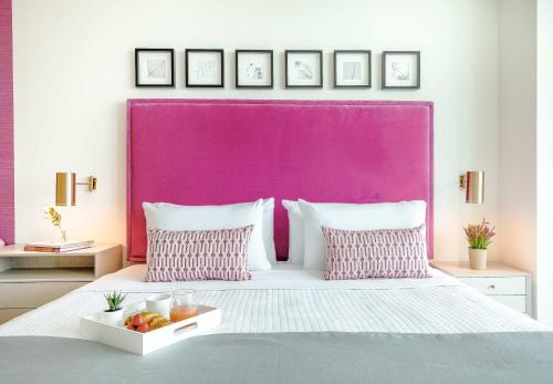 a bed with a pink headboard with a tray of fruit on it at MVR - Wake to Sunrises Toast to Sunsets in Miami