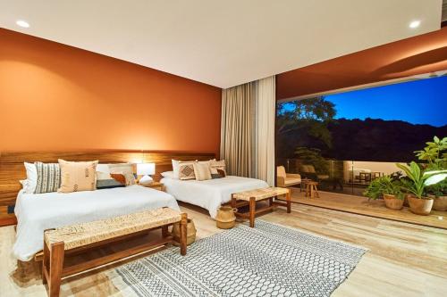 a bedroom with two beds and a large window at Casa Sirenas - Paradise in Puerto Vallarta in Cruz de Huanacaxtle