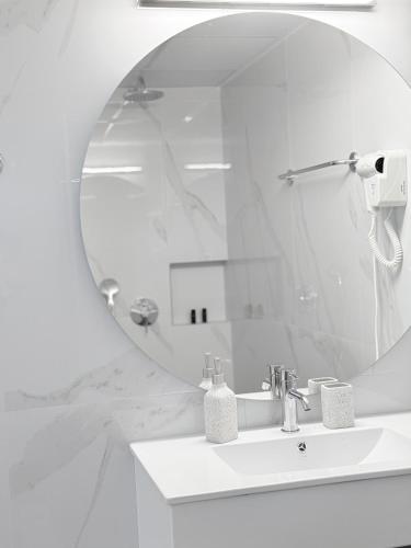 a white bathroom with a sink and a mirror at Avenue Hotel Falassarna in Falasarna