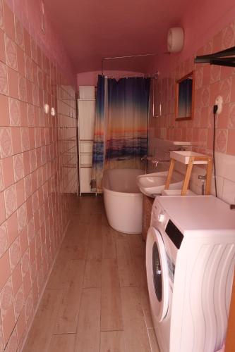 a bathroom with a tub and a washing machine in it at Guest House Relax in Březí