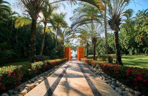 a pathway in a park with palm trees and flowers at Casa Sirenas - Paradise in Puerto Vallarta in Cruz de Huanacaxtle