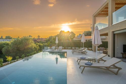 a swimming pool with chairs and umbrellas on a building at Memorial Villa Pessada in Pesádha