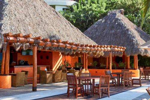 a restaurant with tables and chairs and straw umbrellas at Casa Sirenas - Paradise in Puerto Vallarta in Cruz de Huanacaxtle