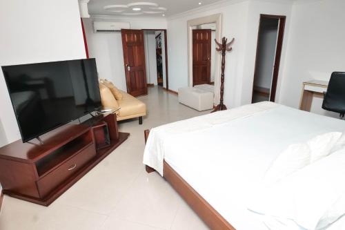 a bedroom with a bed and a flat screen tv at La Casa Blanca Hotel in Buenaventura