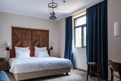 a bedroom with a large bed with blue curtains at AGARANI Estate in Tʼelavi