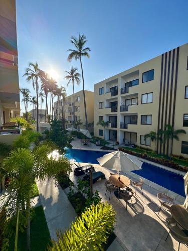 a pool with chairs and umbrellas next to a building at Fantástico Depa en Cerritos OCEANNA frente al MAR ! - 237 AB - in Mazatlán