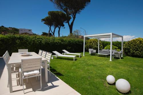 un patio trasero con cenador, mesa y sillas en Dream Villa by the sea, en Porto Santo Stefano