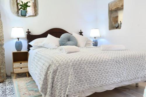 a bedroom with a large white bed with two lamps at Casinha Das Portas