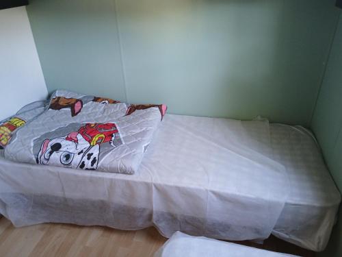 - un lit avec une couette blanche et un oreiller dans l'établissement Mobil-home 415 camping la lande, à Mimizan