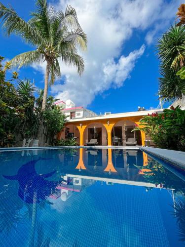a swimming pool in front of a house with palm trees at Troy's House in Cozumel