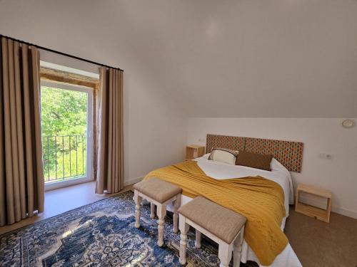a bedroom with a bed with two chairs and a window at Casa Rural Abreu Do Louro in Arbo