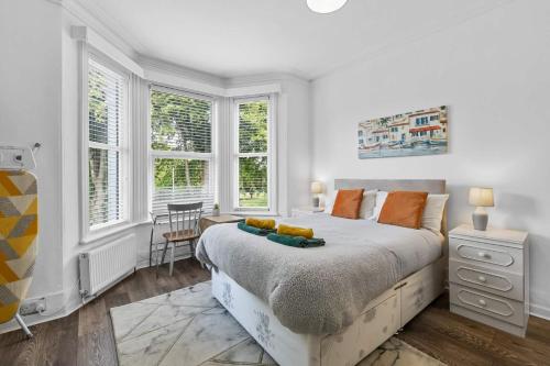 a white bedroom with a large bed and windows at 4 Bed Park View House-Free Parking - Sleep 8 in Plymouth