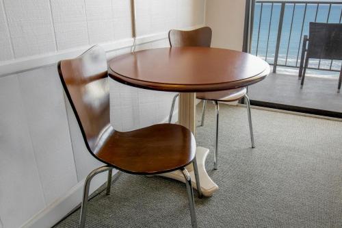 un tavolo in legno e 2 sedie accanto a una finestra di Beaches and Dreams 4th Flr Oceanfront Room a Pawleys Island