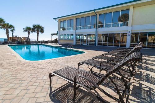 a group of benches next to a building with a pool at Beaches and Dreams 4th Flr Oceanfront Room in Pawleys Island