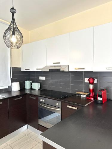a kitchen with white cabinets and a black counter top at Serene Getaway Near Protaras in Paralimni