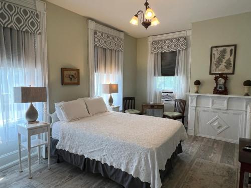 a bedroom with a bed with white sheets and windows at Rogues Harbor Inn in Lansing