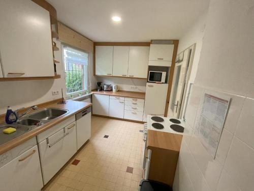 a small kitchen with white cabinets and a sink at Traumferienwohnung Todtmoos - Appartment mit schönem Wintergarten in Todtmoos