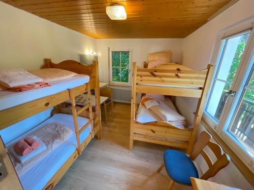 a room with three bunk beds and a chair at Freizeitheim Wilhelm-Kiefer-Haus mit großem Grundstück, Feuerstelle, Tennisplatz in Bad Wildbad