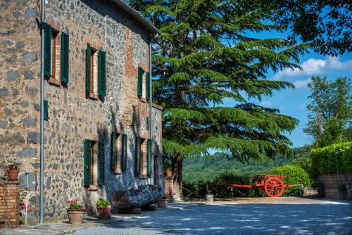 an old stone building with a red wagon next to it at Agriturismo Casale le Crete in Acquapendente