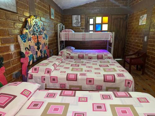 a room with three beds and a brick wall at Román Cabañas del Mirador 4 in Pahuatlán del Valle