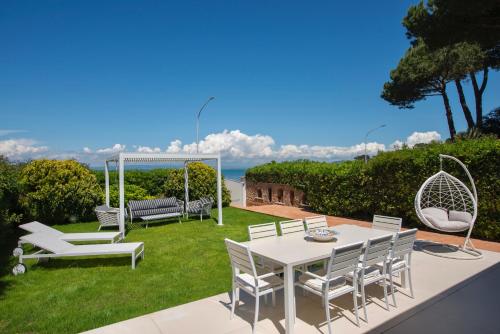 Un patio con una mesa y sillas blancas. en Dream Villa by the sea, en Porto Santo Stefano