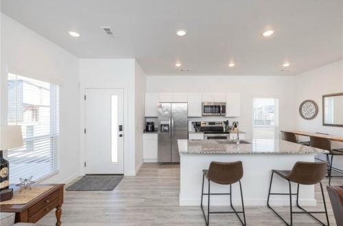 a kitchen with white walls and a counter and chairs at Modern 3BR-Ample Home near Walmart HQ & Downtown in Bentonville