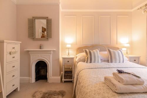 a white bedroom with a bed and a fireplace at The Railway Cottage in Rothley