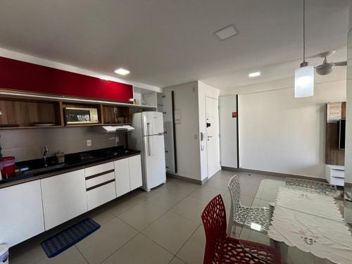 a kitchen with a table and a white refrigerator at Apartamento 2 quartos May Way Meireles uma quadra da Beira-mar in Fortaleza