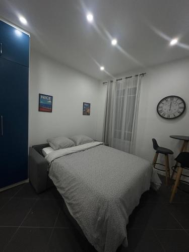 une chambre avec un lit et une horloge au mur dans l'établissement Studio hyper centre Nice, à Nice