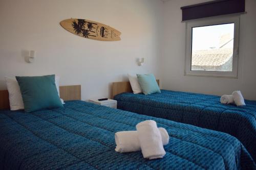 a bedroom with two beds with blue sheets and a window at Casas Ti Flores in Sabugal