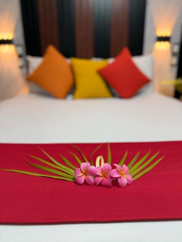 two beds with colorful pillows with flowers on a table at Moatoga Hotel in Apia