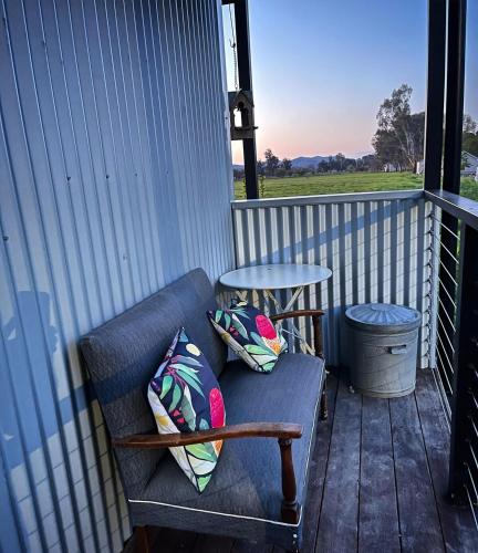 a bench on a porch with pillows and a table at Lume King Valley in Whitfield