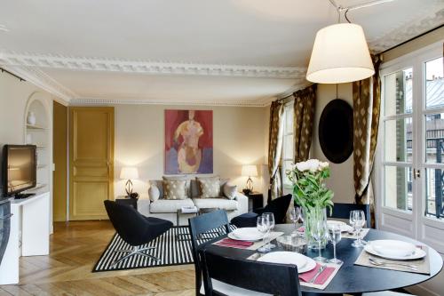 un salon avec une table et des chaises dans l'établissement Paris Louvre Elegant residence, à Paris