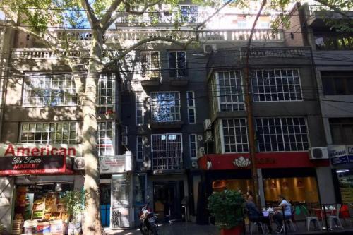 a building on a city street with people sitting in front of it at Loft plaza España in Mendoza