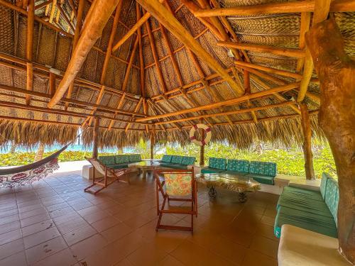 an outdoor pavilion with chairs and tables and a straw roof at Hotel Chiniu in Palomino