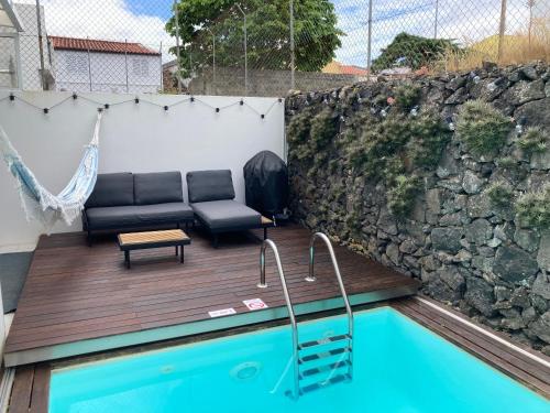 a patio with a couch and a chair next to a pool at Oliveira House in Ponta Delgada