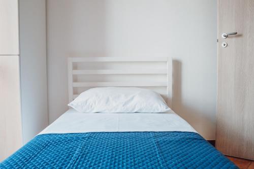 a bed with a blue blanket and a white pillow at Manfredi Apartments in Torre Annunziata