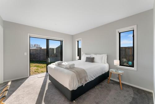 a white bedroom with a large bed and windows at Holiday Hub - Taupo in Taupo