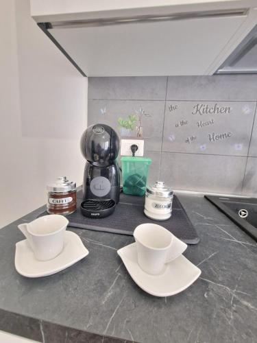 a counter with two cups and a coffee maker at Aura Station Ciampino in Ciampino