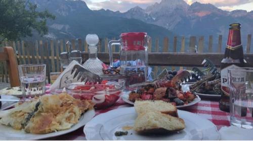 a table with plates of food on a table with mountains at Bujtina Carku in Theth