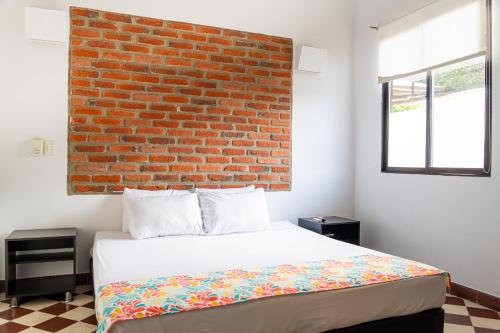 a bedroom with a brick wall and a bed at Hotel Puerto Pelicano in Santa Marta