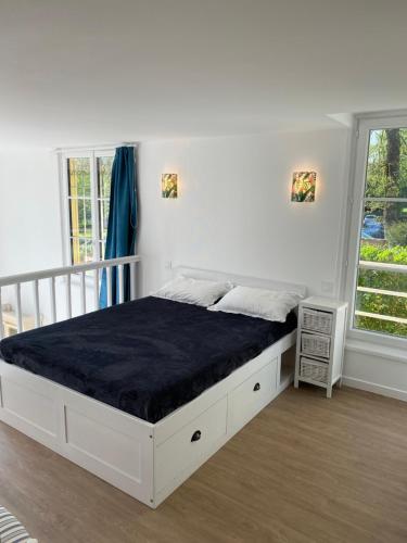 un lit blanc dans une chambre blanche avec une fenêtre dans l'établissement Appartement Hortensia, à Bagnoles-de-l'Orne