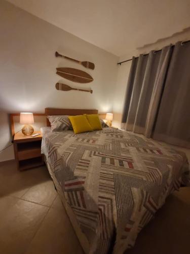 a bedroom with a large bed with a yellow pillow at Falésias de Pipa - Apto 205 in Pipa