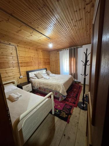 a bedroom with two beds and a wooden ceiling at Bujtina Carku in Theth