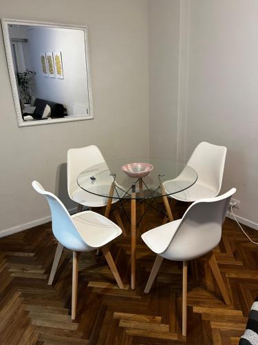 a dining room with white chairs and a glass table at Departamento Plaza Colón Yeyita in Mar del Plata