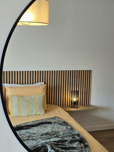 a mirror reflecting a bed with a pillow and a lamp at Paim Lodge in Ponta Delgada